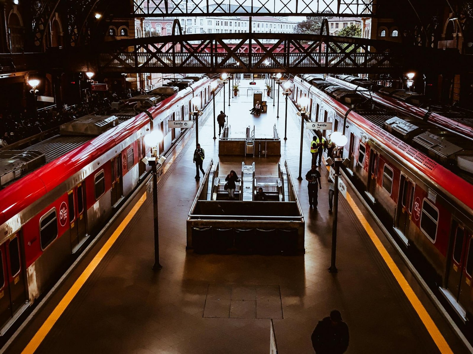 A bustling railway station with modern trains and commuters moving through the terminal.