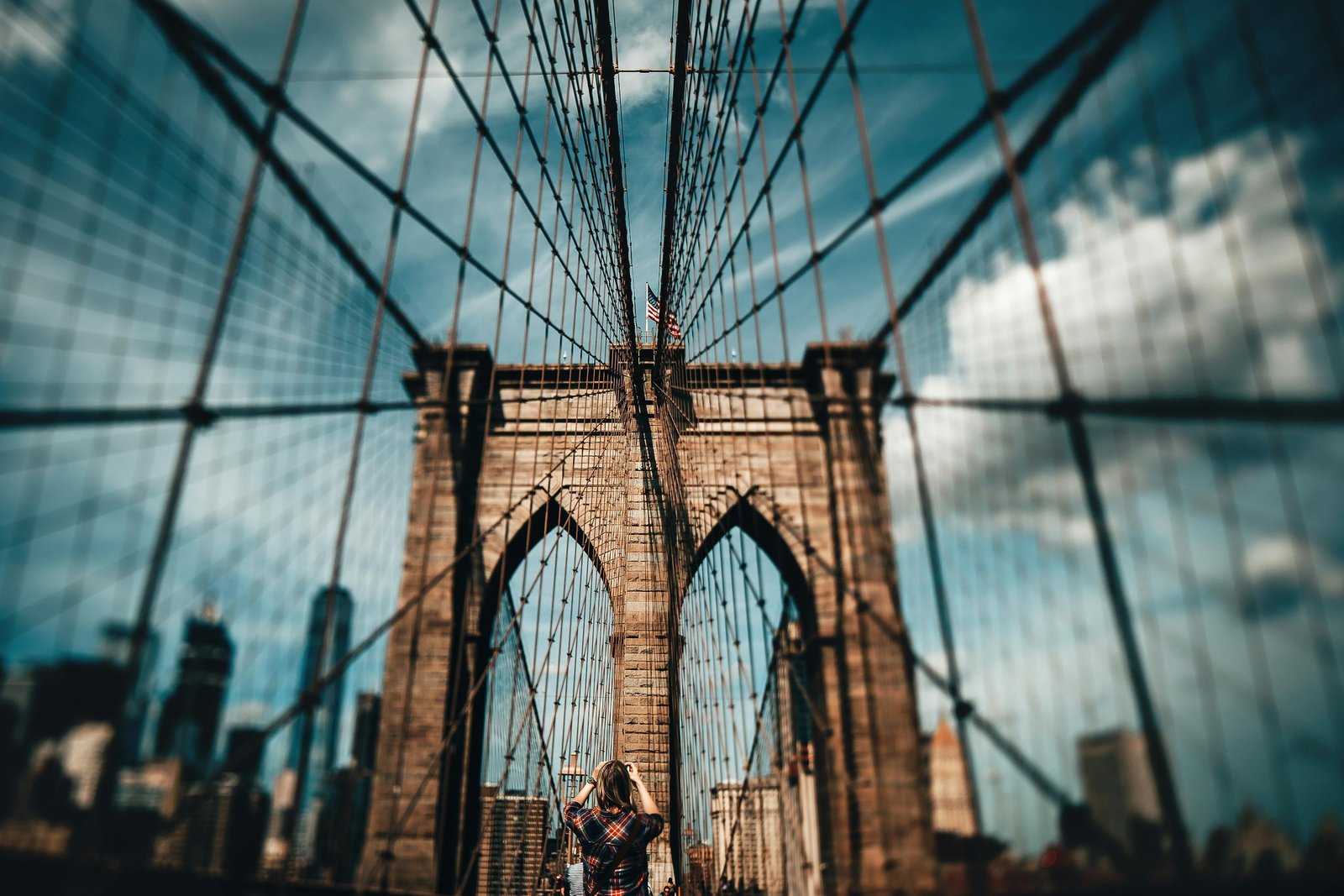 A photographer captures the iconic Brooklyn Bridge against a dramatic New York City skyline.